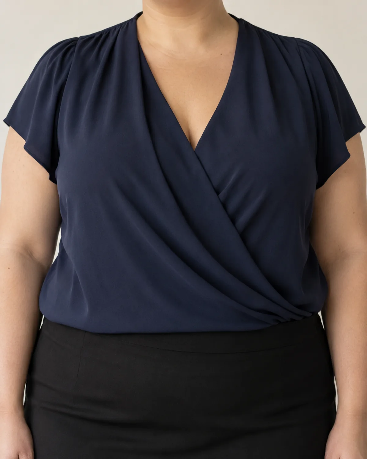 Close-up of a draped-front blouse neckline with a mock-wrap V shape, showing the drape sitting flat against the collarbone